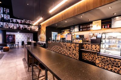 Hall spacieux avec sol en marbre, comptoirs modernes, mezzanine jaune et éclairage suspendu.