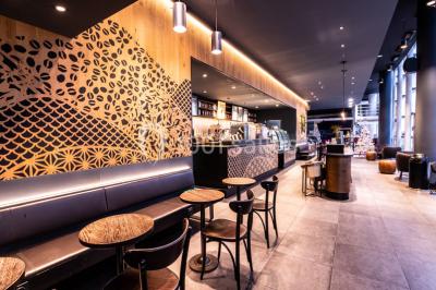 Hall spacieux avec sol en marbre, comptoirs modernes, mezzanine jaune et éclairage suspendu.