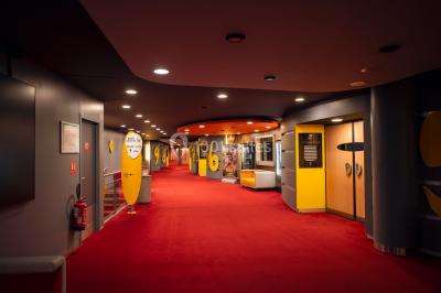 Hall spacieux avec sol en marbre, comptoirs modernes, mezzanine jaune et éclairage suspendu.