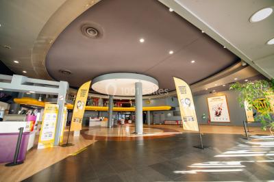 Hall spacieux avec sol en marbre, comptoirs modernes, mezzanine jaune et éclairage suspendu.