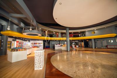 Hall spacieux avec sol en marbre, comptoirs modernes, mezzanine jaune et éclairage suspendu.