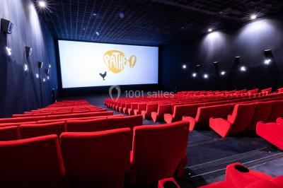 Façade d'un cinéma IMAX moderne avec parking vide au premier plan et ciel nuageux en arrière-plan.