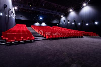 Façade d'un cinéma IMAX moderne avec parking vide au premier plan et ciel nuageux en arrière-plan.