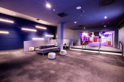 Façade d'un cinéma IMAX moderne avec parking vide au premier plan et ciel nuageux en arrière-plan.