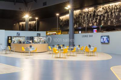 Salle de cinéma vide avec des rangées de sièges rouges et un grand écran blanc allumé.