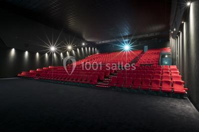 Salle de cinéma avec sièges rouges et grand écran affichant le logo IMAX, éclairage tamisé.