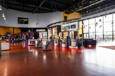 Salle de cinéma avec sièges rouges et grand écran affichant le logo IMAX, éclairage tamisé.