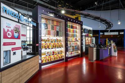 Salle de cinéma avec sièges rouges et grand écran affichant le logo IMAX, éclairage tamisé.