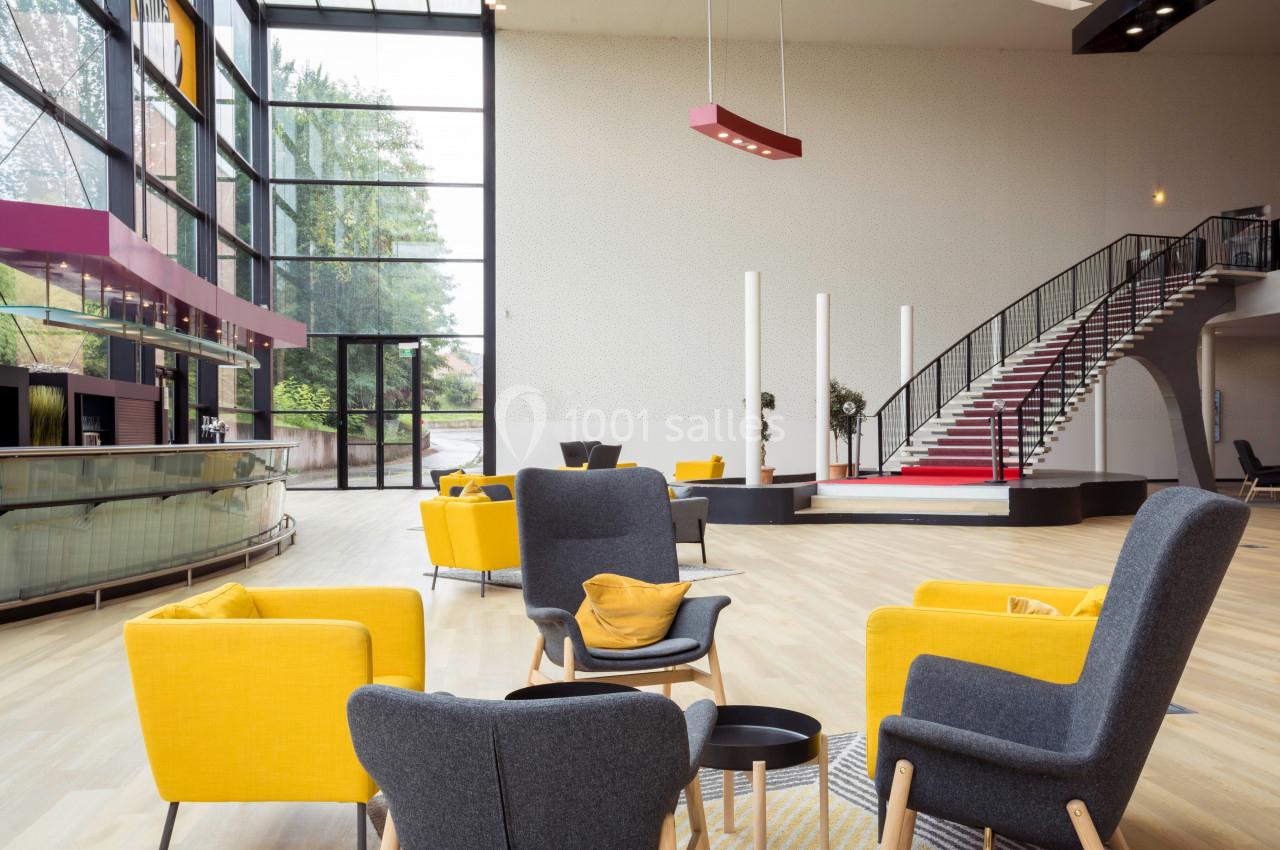 Espace intérieur lumineux avec fauteuils jaunes et gris, escalier en colimaçon et grandes baies vitrées donnant sur l…