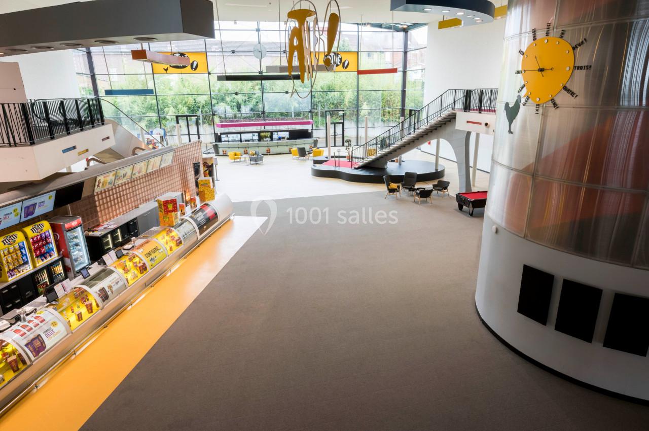 Vue intérieure d'un espace lumineux avec des présentoirs de produits, une aire de jeux et de grandes baies vitrées.