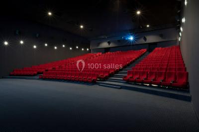 Salle de cinéma vide avec rangées de fauteuils rouges, éclairage tamisé et écran hors champ.