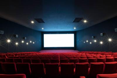 Salle de cinéma vide avec rangées de fauteuils rouges, éclairage tamisé et écran hors champ.