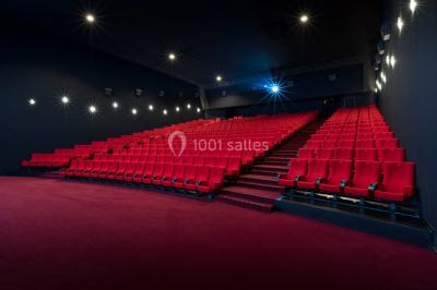 Salle de cinéma vide avec rangées de fauteuils rouges, éclairage tamisé et écran hors champ.