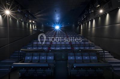 Salle de cinéma moderne avec sièges inclinables, éclairage tamisé et projecteur allumé.