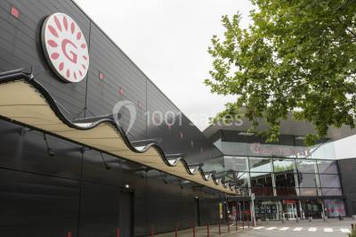 Salle de cinéma moderne avec sièges inclinables, éclairage tamisé et projecteur allumé.