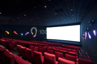 Salle de cinéma moderne avec sièges inclinables, éclairage tamisé et projecteur allumé.