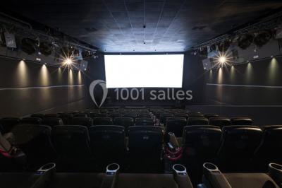 Salle de cinéma moderne avec sièges inclinables, éclairage tamisé et projecteur allumé.