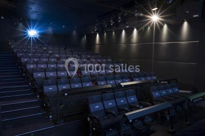 Salle de cinéma moderne avec sièges inclinables, éclairage tamisé et projecteur allumé.