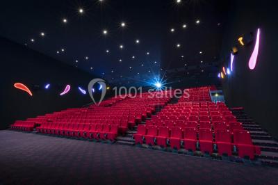 Salle de cinéma moderne avec sièges inclinables, éclairage tamisé et projecteur allumé.
