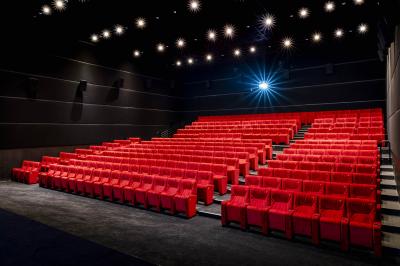 Couloir lumineux avec moquette grise, fauteuils, murs sombres, panneaux jaunes et ascenseurs numérotés 10.