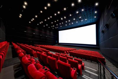 Couloir lumineux avec moquette grise, fauteuils, murs sombres, panneaux jaunes et ascenseurs numérotés 10.