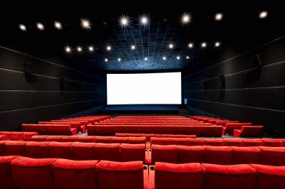 Couloir lumineux avec moquette grise, fauteuils, murs sombres, panneaux jaunes et ascenseurs numérotés 10.