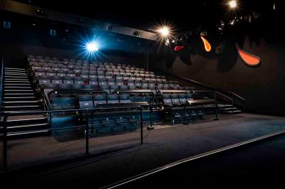 Façade d'un cinéma Pathé illuminée au crépuscule, avec des bâtiments en arrière-plan et des traînées lumineuses de voitures.