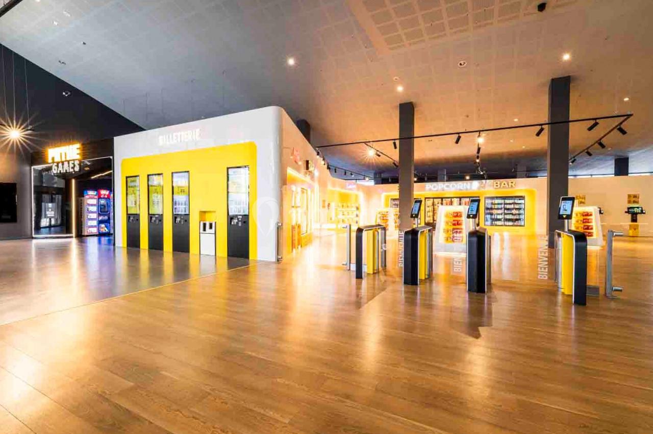 Vue d'un espace lumineux avec des bornes automatiques, un comptoir de snacks et des distributeurs alignés.