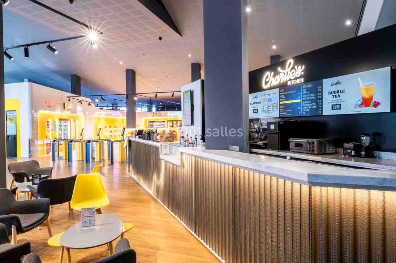 Comptoir de restauration moderne avec menu affiché, chaises colorées et éclairage lumineux dans un espace ouvert.