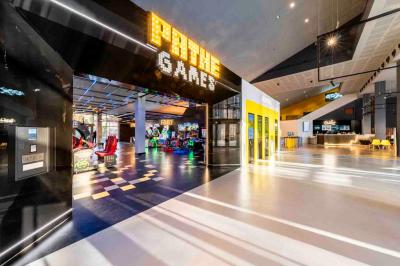 Façade d'un cinéma Pathé illuminée au crépuscule, avec des bâtiments en arrière-plan et des traînées lumineuses de voitures.