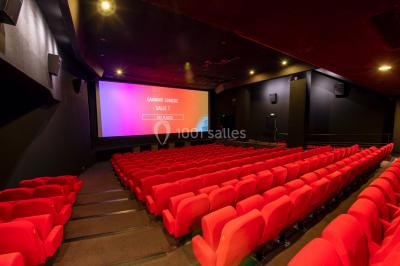 Façade d'un cinéma Gaumont avec des affiches de films et des parasols rouges devant l'entrée.