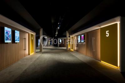 Deux fauteuils et une table basse dans un espace moderne avec un ascenseur encadré de lumière jaune au fond.