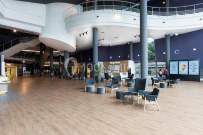Deux fauteuils et une table basse dans un espace moderne avec un ascenseur encadré de lumière jaune au fond.