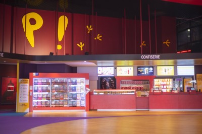 Salle de cinéma vide avec rangées de fauteuils rouges alignés face à un écran non visible.