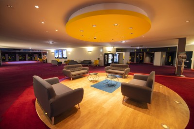 Salle de cinéma vide avec rangées de fauteuils rouges alignés face à un écran non visible.