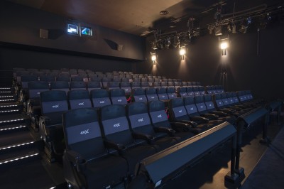 Salle de cinéma vide avec rangées de fauteuils rouges alignés face à un écran non visible.
