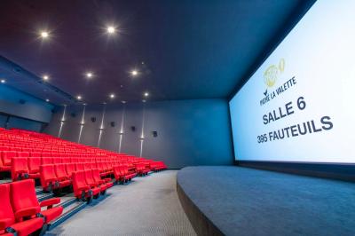 Salle de cinéma IMAX avec 520 fauteuils rouges, écran géant et éclairage tamisé.