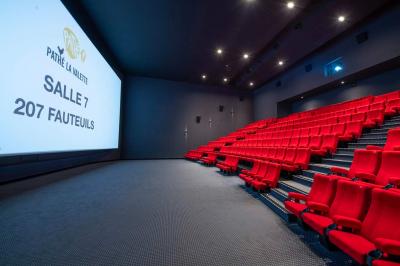 Salle de cinéma IMAX avec 520 fauteuils rouges, écran géant et éclairage tamisé.