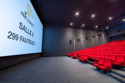 Salle de cinéma IMAX avec 520 fauteuils rouges, écran géant et éclairage tamisé.
