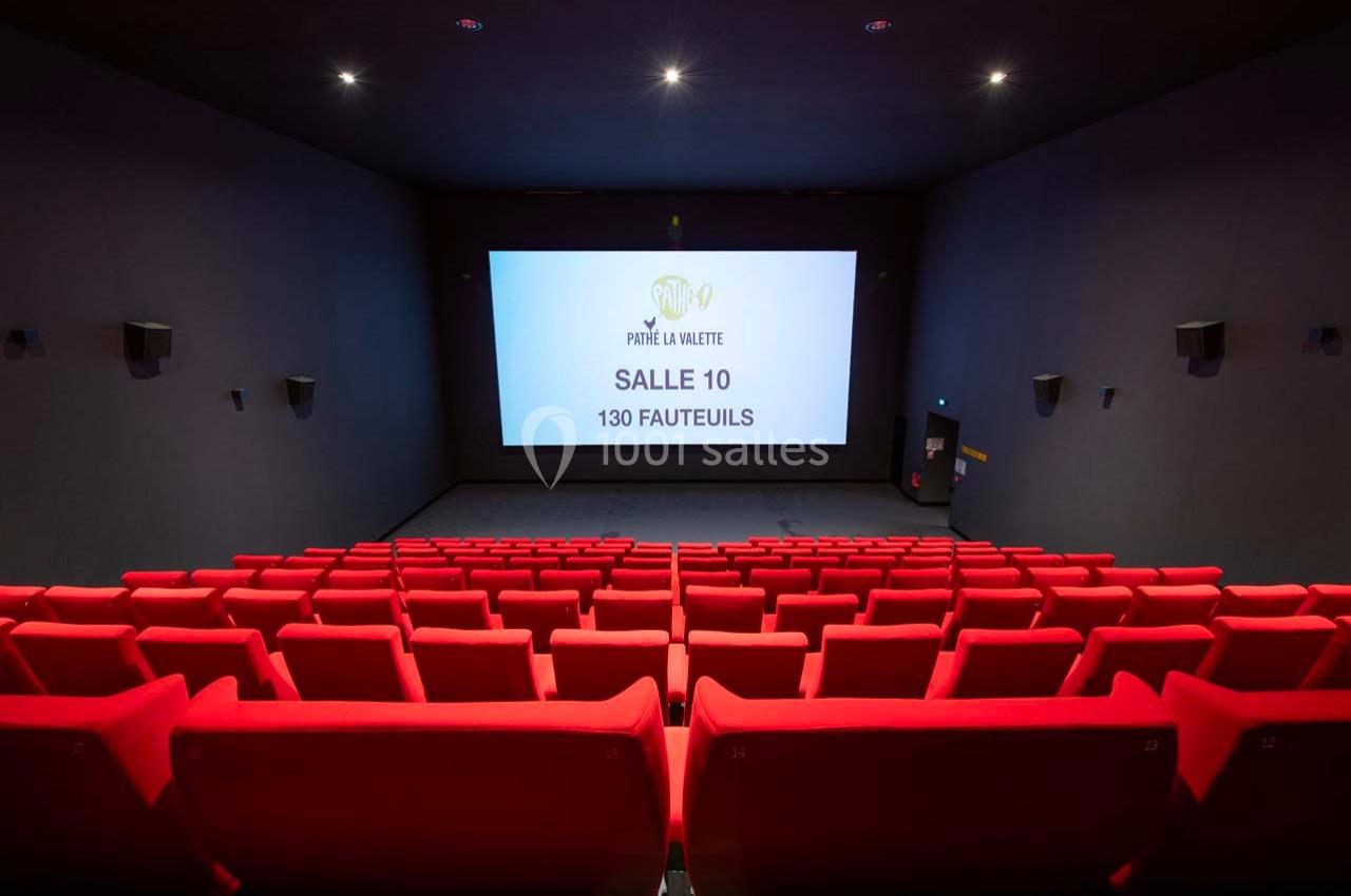 Salle de cinéma vide avec des rangées de fauteuils rouges et un écran affichant ’Salle 10, 130 fauteuils’.