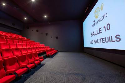 Salle de cinéma IMAX avec 520 fauteuils rouges, écran géant et éclairage tamisé.