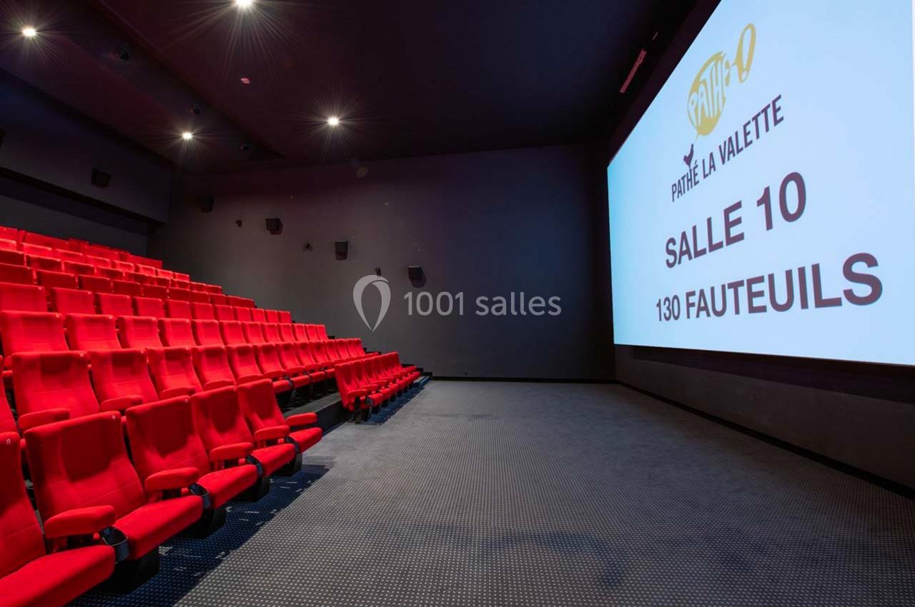 Salle de cinéma vide avec des rangées de fauteuils rouges et un écran affichant ’Salle 10, 130 fauteuils’.
