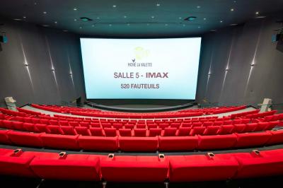 Salle de cinéma IMAX avec 520 fauteuils rouges, écran géant et éclairage tamisé.