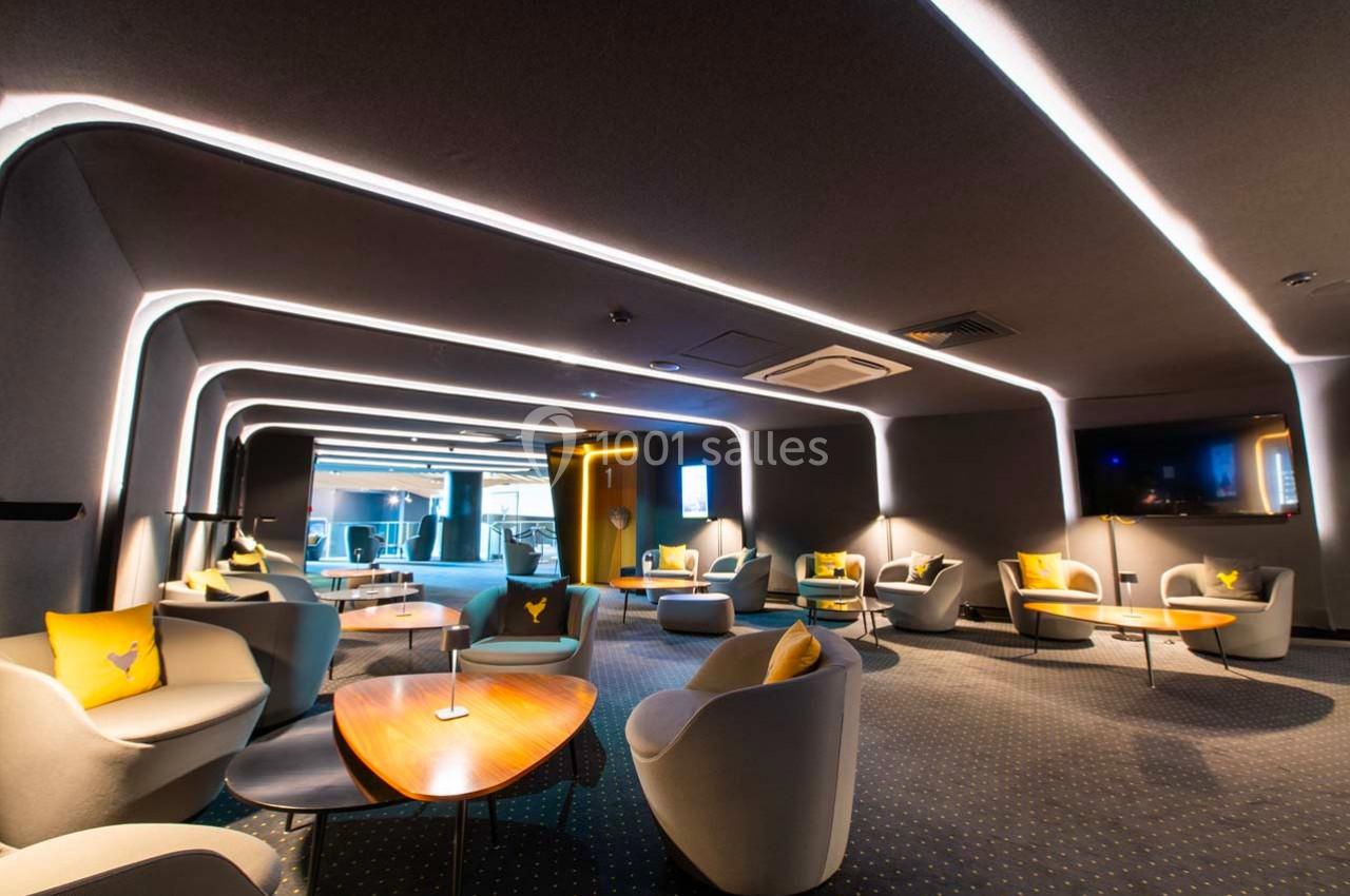 Espace lounge moderne avec fauteuils, tables basses en bois, éclairage LED et ambiance feutrée.