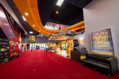 Salle colorée avec moquette violette et orange, plafond circulaire rouge, chaises modernes et affiches murales.