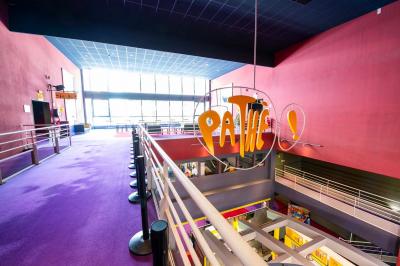 Salle colorée avec moquette violette et orange, plafond circulaire rouge, chaises modernes et affiches murales.