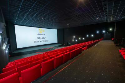 Salle colorée avec moquette violette et orange, plafond circulaire rouge, chaises modernes et affiches murales.