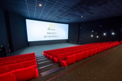 Salle colorée avec moquette violette et orange, plafond circulaire rouge, chaises modernes et affiches murales.