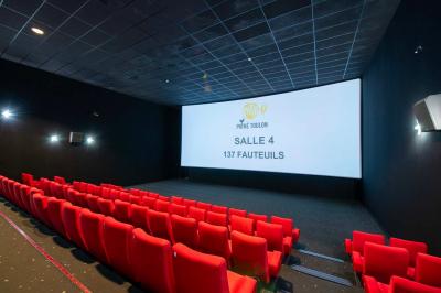 Salle colorée avec moquette violette et orange, plafond circulaire rouge, chaises modernes et affiches murales.