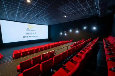 Salle colorée avec moquette violette et orange, plafond circulaire rouge, chaises modernes et affiches murales.